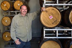 Winemaker Dave Nagengast standing in front of wine barrels